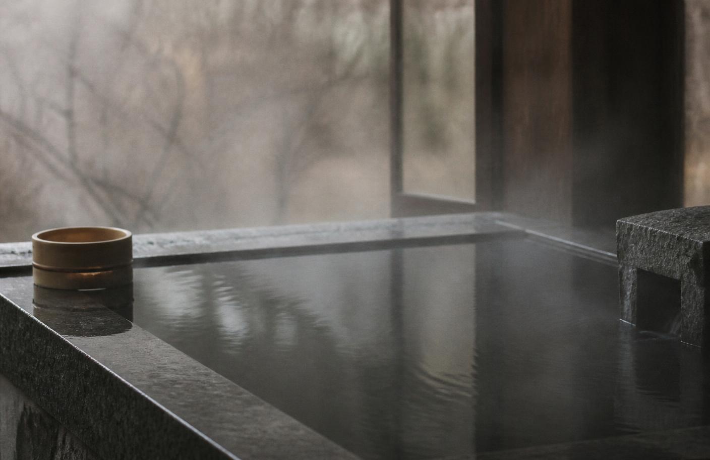Still cold water in a dark stone tub with faint mist rising in early morning light.